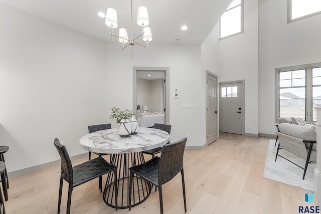 dining room with light wood-type flooring, a high ceiling, and a chandelier