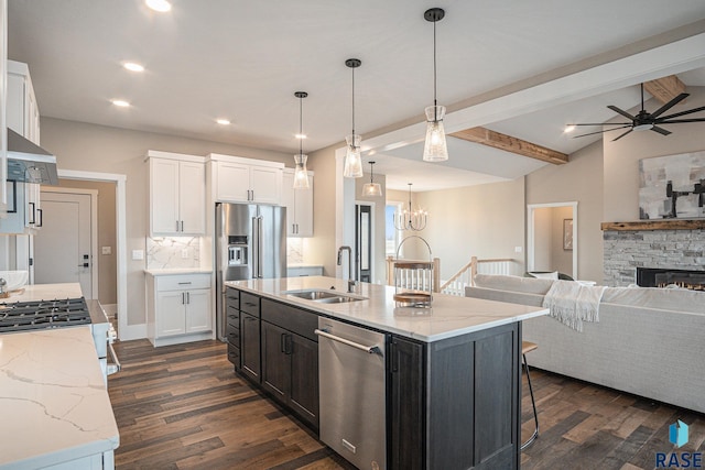 kitchen featuring dark hardwood / wood-style floors, a fireplace, stainless steel appliances, a kitchen island with sink, and sink