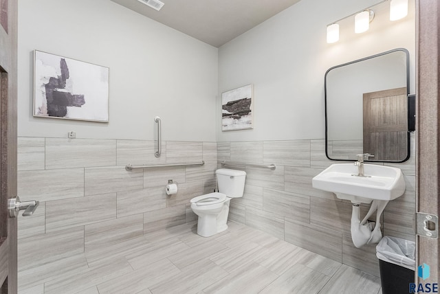 bathroom featuring toilet, tile patterned flooring, sink, and tile walls