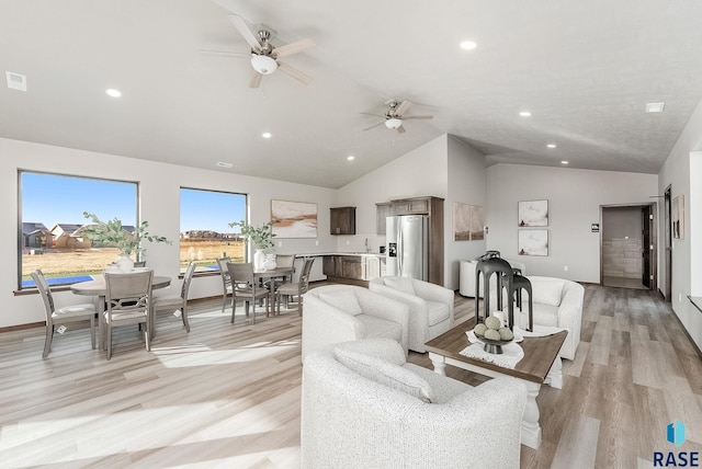 living room with vaulted ceiling, ceiling fan, and light wood-type flooring