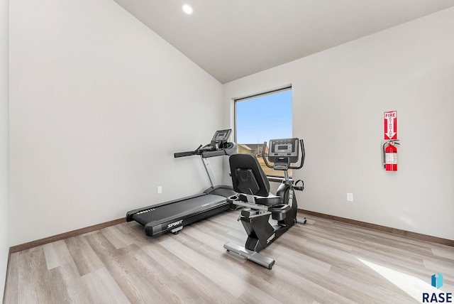 exercise room with lofted ceiling and light hardwood / wood-style floors