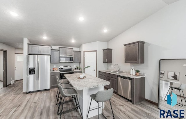 kitchen featuring a breakfast bar, sink, light hardwood / wood-style flooring, a kitchen island, and stainless steel appliances