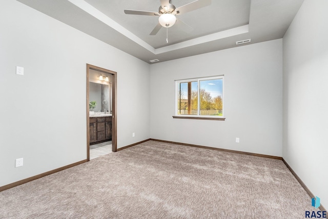 carpeted spare room with ceiling fan and a tray ceiling