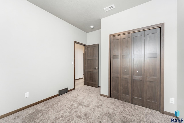 unfurnished bedroom with a closet and light carpet