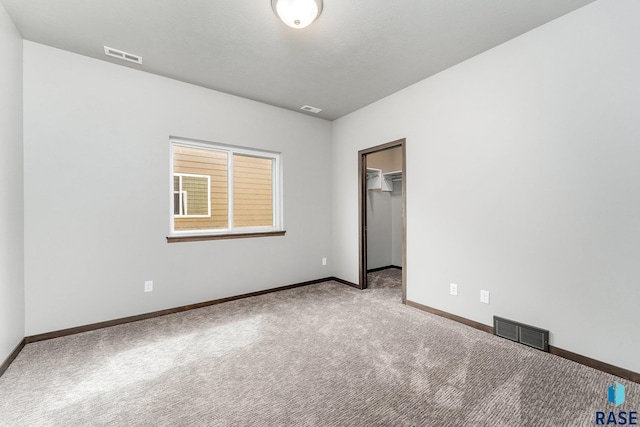 unfurnished bedroom featuring a spacious closet, a closet, and carpet