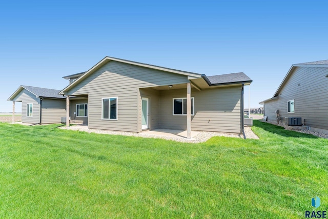 rear view of house featuring central air condition unit, a patio, and a lawn