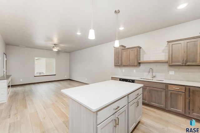 kitchen featuring sink, ceiling fan, tasteful backsplash, hanging light fixtures, and a kitchen island