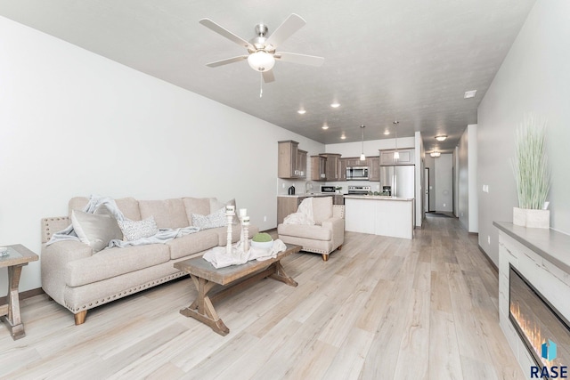 living room featuring sink, ceiling fan, and light hardwood / wood-style floors