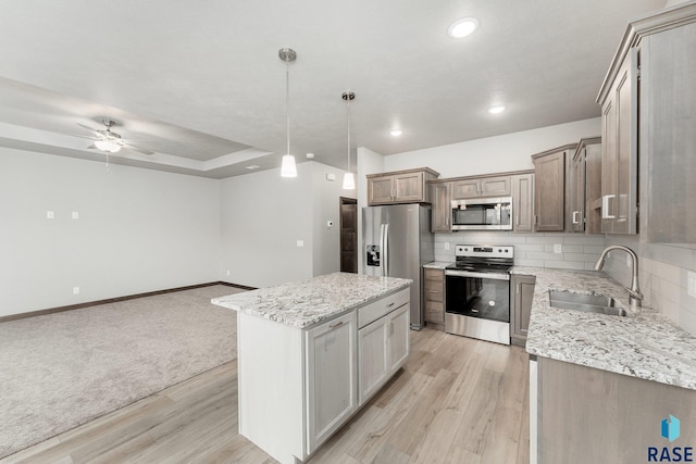 kitchen with a center island, hanging light fixtures, sink, light hardwood / wood-style flooring, and stainless steel appliances