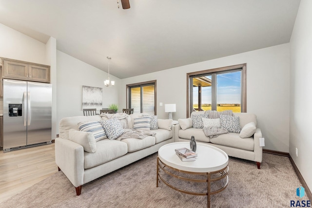 living room featuring light hardwood / wood-style floors, ceiling fan with notable chandelier, and vaulted ceiling