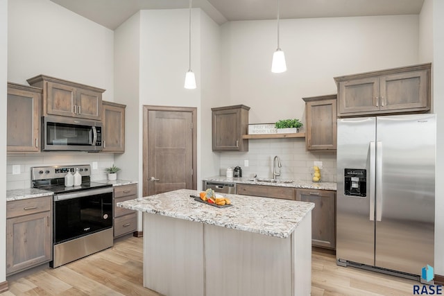 kitchen featuring backsplash, high vaulted ceiling, stainless steel appliances, and light hardwood / wood-style flooring