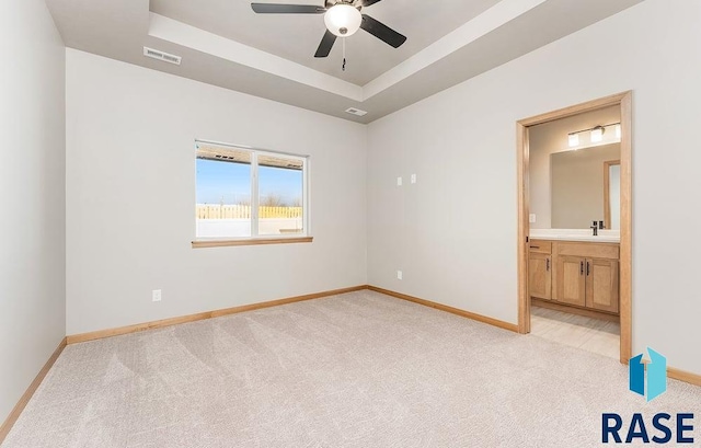 1437 N Mae Pl, Tea, SD 57064 - unfurnished bedroom featuring connected bathroom, light colored carpet, ceiling fan, and a tray ceiling