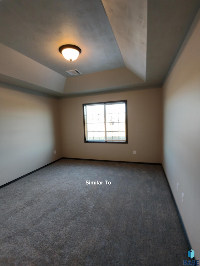 carpeted empty room featuring a raised ceiling