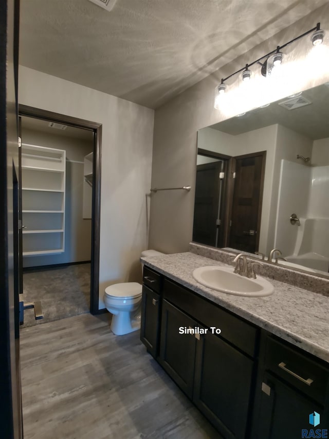 bathroom with toilet, a shower, hardwood / wood-style floors, and vanity