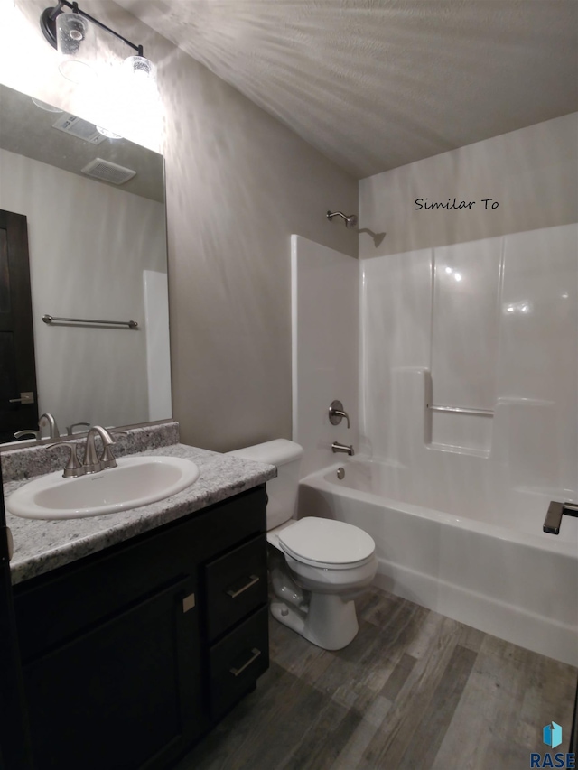 full bathroom with hardwood / wood-style floors, shower / bathing tub combination, a textured ceiling, vanity, and toilet