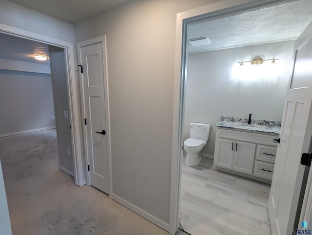 bathroom featuring concrete flooring, a textured ceiling, vanity, and toilet