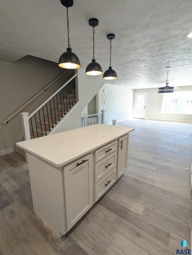 kitchen with hanging light fixtures, white cabinetry, and light wood-type flooring