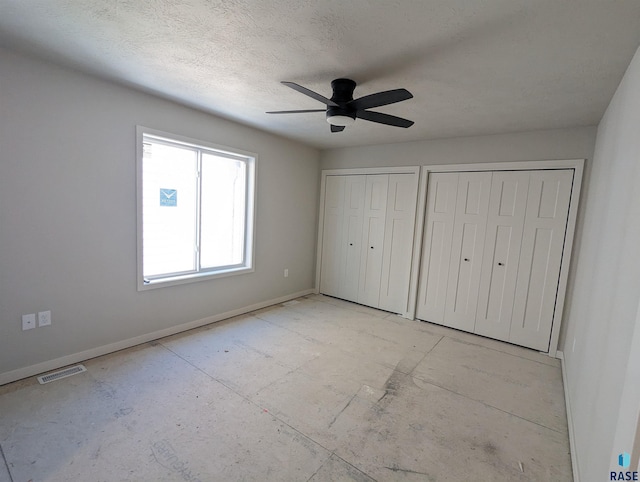 unfurnished bedroom featuring ceiling fan and multiple closets