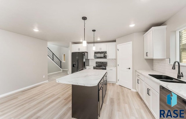 kitchen featuring white cabinets, a center island, sink, and black appliances