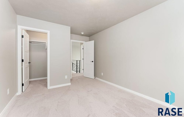 unfurnished bedroom featuring a walk in closet, light colored carpet, and a closet