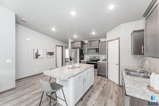 kitchen featuring sink, stainless steel appliances, light hardwood / wood-style flooring, a kitchen bar, and a kitchen island