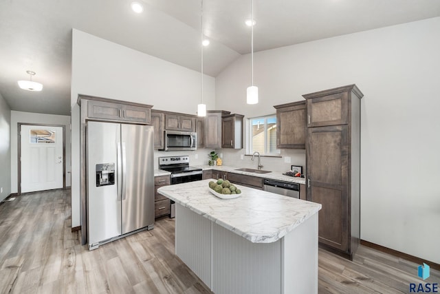 kitchen featuring sink, decorative light fixtures, a center island, light hardwood / wood-style flooring, and appliances with stainless steel finishes