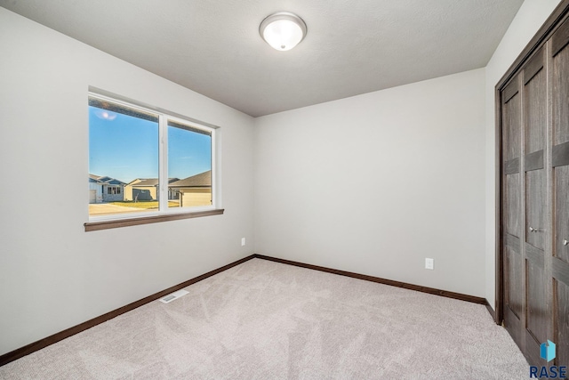 unfurnished bedroom with light colored carpet and a closet