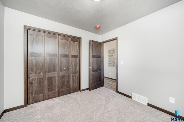 unfurnished bedroom with carpet flooring, a textured ceiling, and a closet