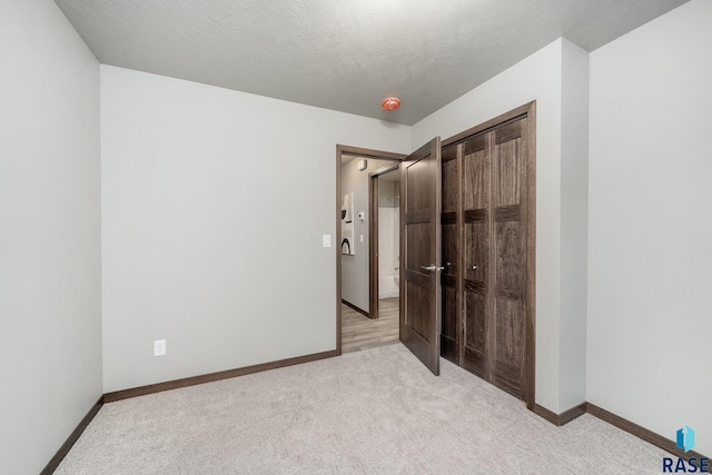 unfurnished bedroom with light colored carpet, a closet, and a textured ceiling