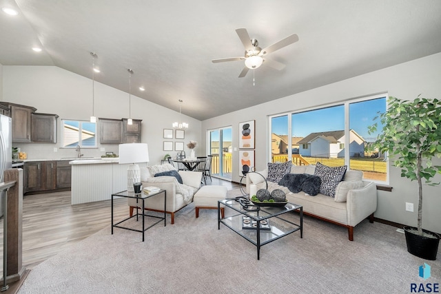 living room with sink, ceiling fan with notable chandelier, plenty of natural light, and light wood-type flooring