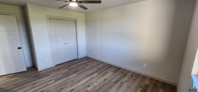 unfurnished bedroom featuring a closet, wood-type flooring, and ceiling fan