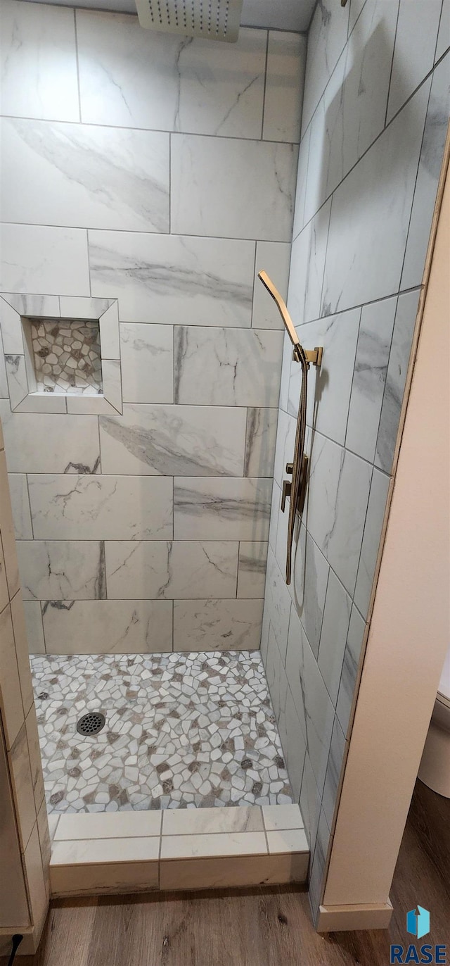 bathroom with wood-type flooring and a tile shower