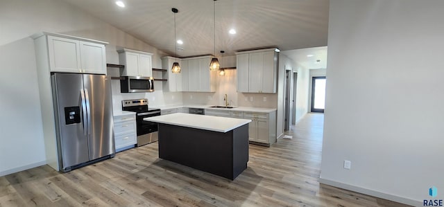 kitchen with appliances with stainless steel finishes, sink, a kitchen island, light hardwood / wood-style floors, and lofted ceiling