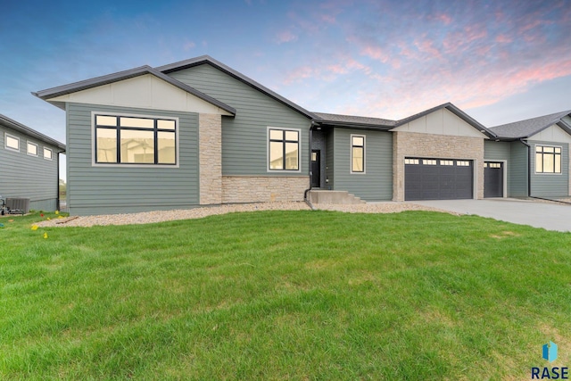 view of front of house featuring a yard, a garage, and central AC unit