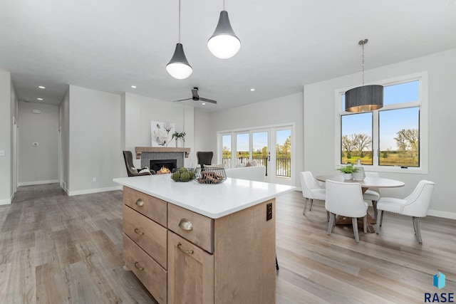 kitchen with ceiling fan, pendant lighting, light hardwood / wood-style flooring, and a center island