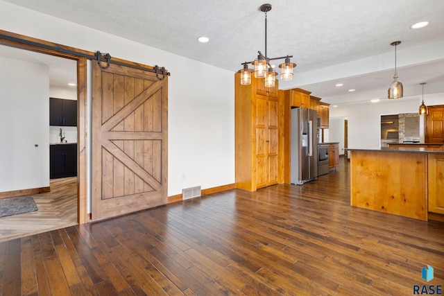 unfurnished living room with a barn door, sink, a textured ceiling, and dark hardwood / wood-style flooring