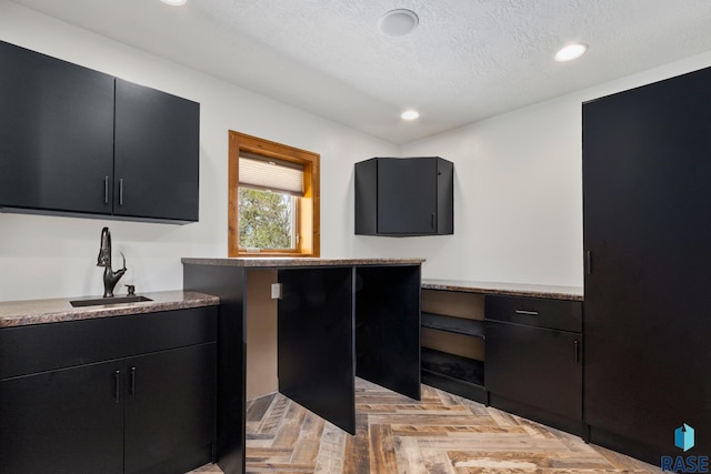 kitchen featuring light parquet floors, a textured ceiling, and sink