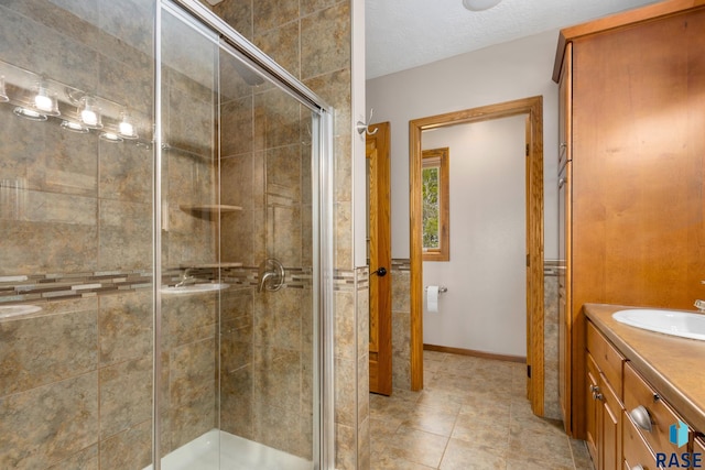 bathroom featuring tile floors, walk in shower, a textured ceiling, and vanity