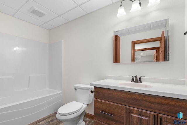 full bathroom featuring washtub / shower combination, a paneled ceiling, hardwood / wood-style floors, vanity, and toilet