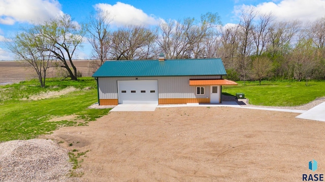 view of front of property featuring a garage, a front lawn, and an outdoor structure