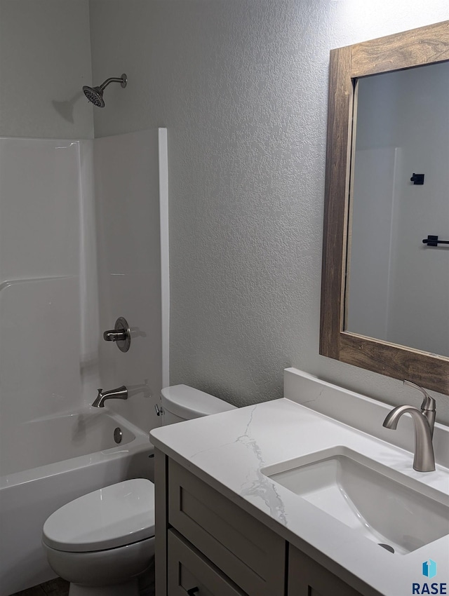 bathroom with a textured wall, shower / tub combination, vanity, and toilet