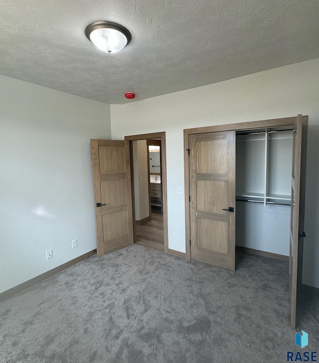 unfurnished bedroom featuring a textured ceiling, a closet, carpet flooring, and baseboards