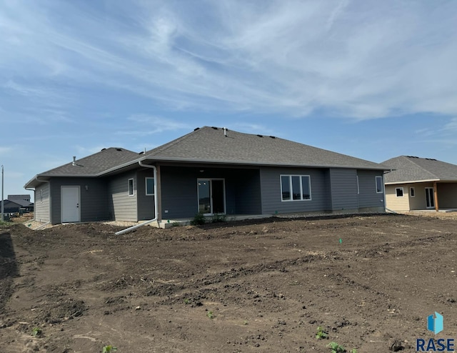 rear view of house with roof with shingles