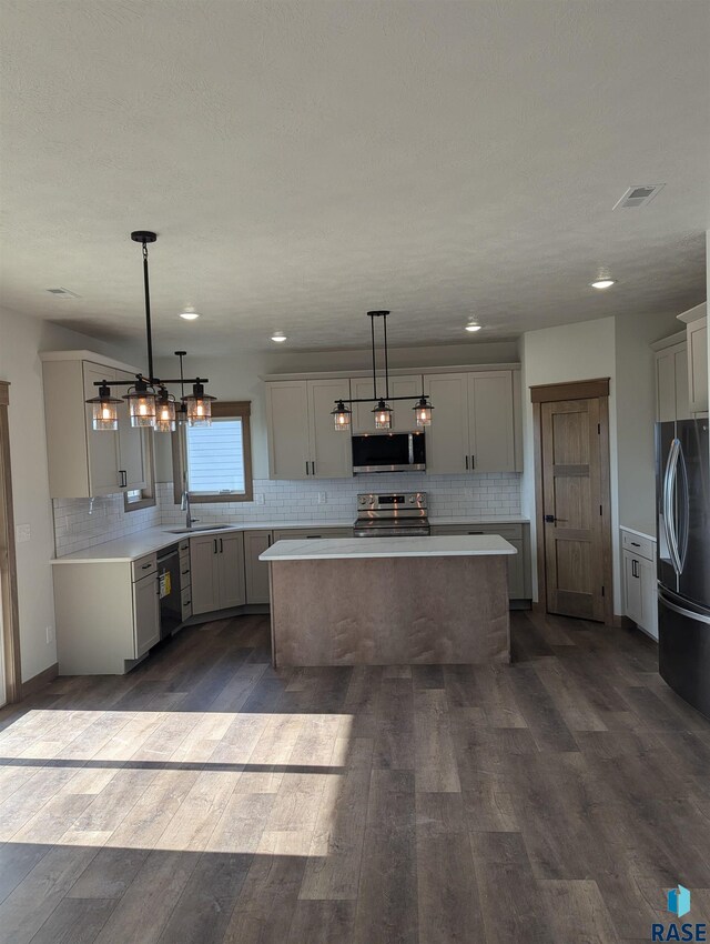 kitchen with hanging light fixtures, a kitchen island, dark hardwood / wood-style flooring, and black appliances