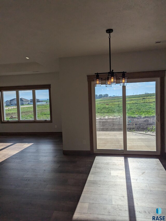 unfurnished dining area with a notable chandelier and wood-type flooring