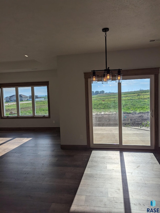 unfurnished dining area with a notable chandelier and hardwood / wood-style floors