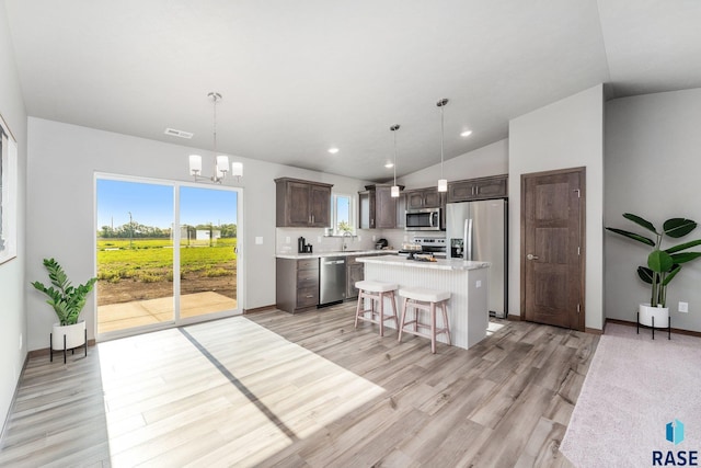 kitchen featuring a kitchen breakfast bar, a kitchen island, stainless steel appliances, and decorative light fixtures