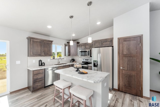 kitchen featuring pendant lighting, a center island, backsplash, sink, and appliances with stainless steel finishes