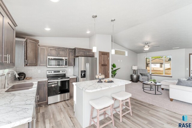 kitchen featuring a center island, backsplash, sink, ceiling fan, and appliances with stainless steel finishes