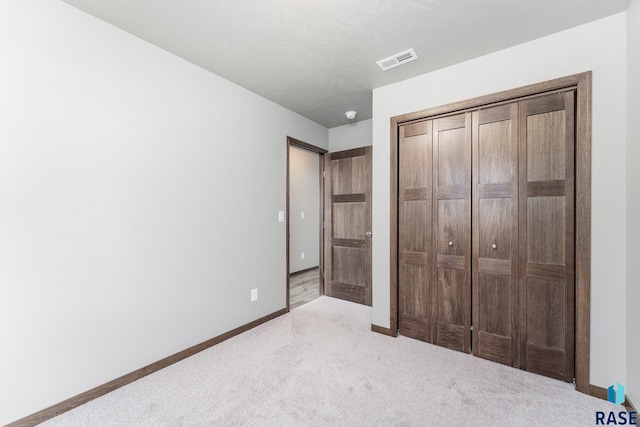 unfurnished bedroom with light carpet and a closet